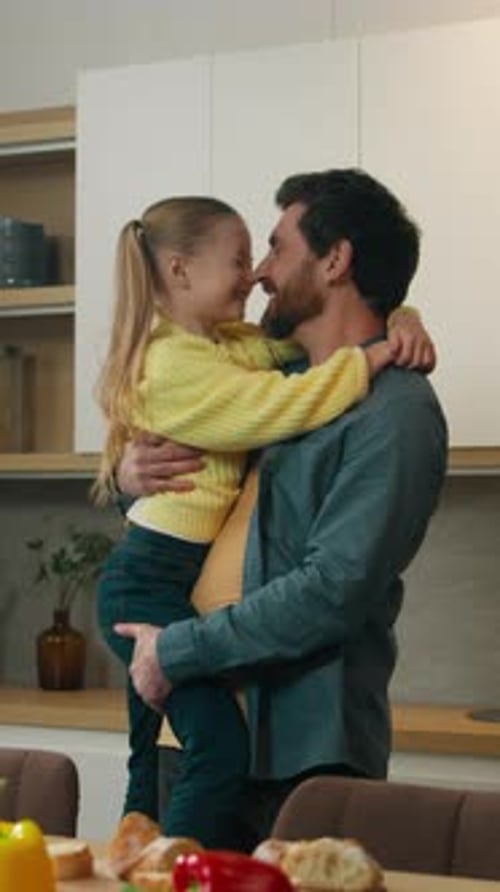 Affectionate Father Holding and Hugging His Daughter in Kitchen