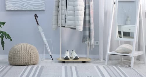 Différents vêtements accrochés à un support, accessoires et baskets à l'intérieur, caméra se déplaçant vers le haut