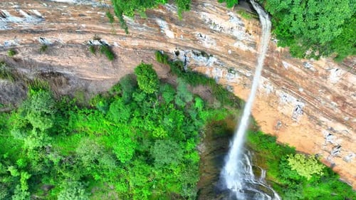 Drone captures majestic waterfall cascading from cliff.