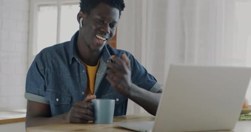 Man Smiling on Video Call with Laptop at Home