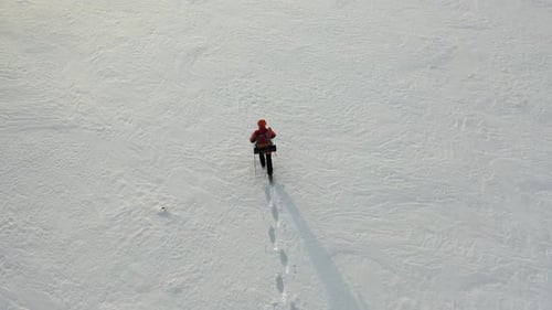 Footage View From Drone a Lone Traveler with a Backpack Walks Through the Snowy Desert