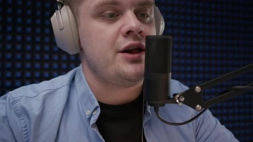 Close Up View of Young Radio Host in Headphones Who Sits in Recording Studio in Blue Shirt and