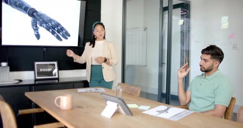Presenting robotic hand design, woman speaking to colleague in modern office