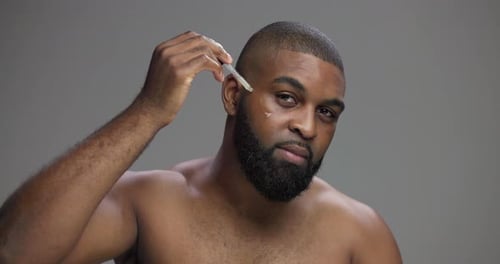 Man Applying Serum with Dropper for Facial Care