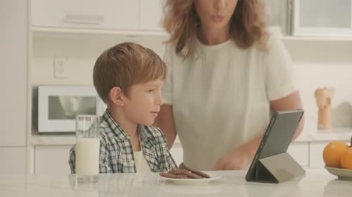 Boy Enjoys Tablet with Mother in Bright Kitchen