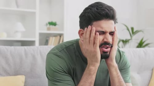 Hindu Guy Gesturing From Frustration While Sitting on Couch