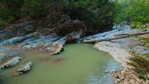 Serene forest creek with rocky waterfall and clear turquoise water nature scene