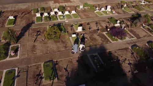 Woman and man praying in front of grave during sunny day at cemetery in Buenos Aires