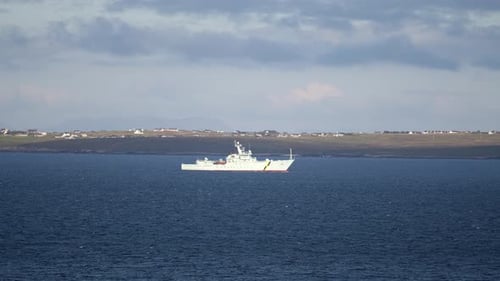 Telephoto shot of a Coastguard fisheries patrol vessel sailing over choppy water through the inlet o