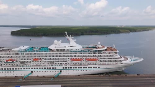 Aerial view of a large cruise ship docked at a port with expansive views of the surrounding water an