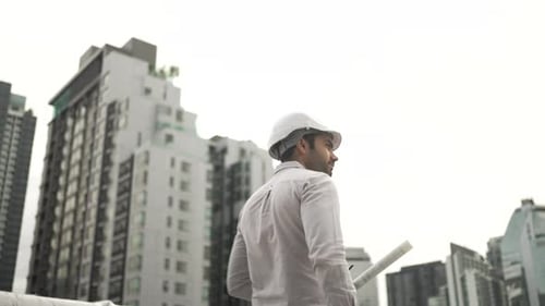 Engineer is working on the rooftop of high rise building.