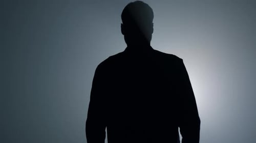 Silhouette of Man Walking Toward Bright Light