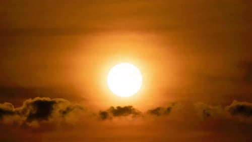 Bright Sun Glowing Through a Cloudy Orange Sky