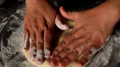 Draufsicht einer weiblichen Hand bei der Zubereitung von Pizza, Pizzateig