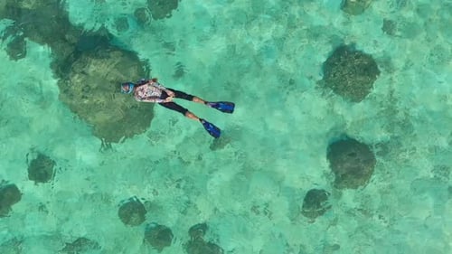 Vue aérienne d'une femme faisant de la plongée en apnée parmi les coraux, Maldives.