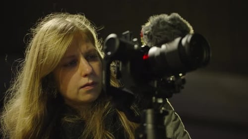 Woman Adjusting Professional Camera on Tripod