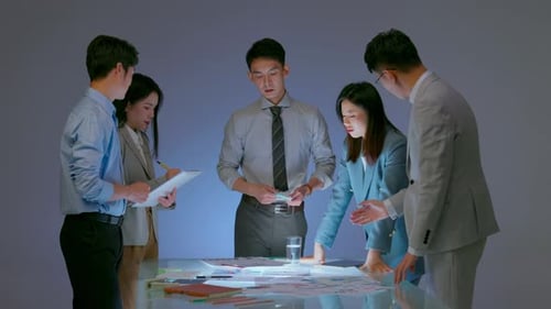 Team of business people working together at office desk discussions revolving around financial chart