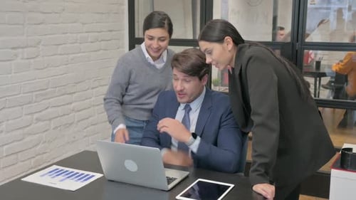 Colleagues Collaborating Around Laptop in Modern Office
