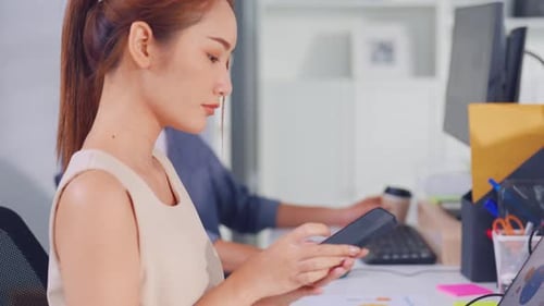 Asian happy businesswoman talking on smartphone and working in office.