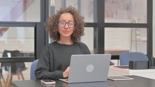 Woman Smiles While Working on Laptop at Desk
