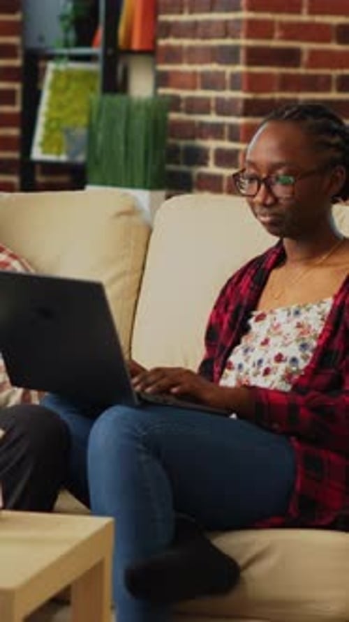 Woman Works on Laptop As Man Relaxes