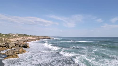 Rocky Shore and Waves Crashing along the Ocean Coast. Daytime. Drone Aerial Sweep.