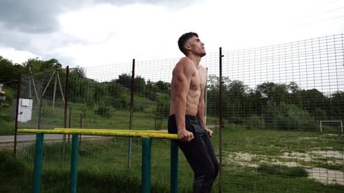 Muscular Man Doing Abs Exercises on Parallel Bars