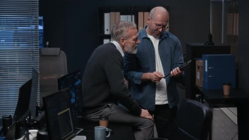 Dois trabalhadores de segurança cibernética discutindo enquanto olham para um tablet digital no escritório