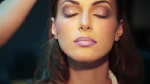 Woman having makeup applied by makeup artist