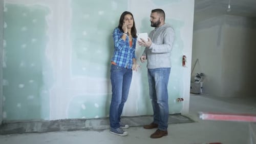Two Architects with Tablet and Cellphone Working at Their New Home Analyzing