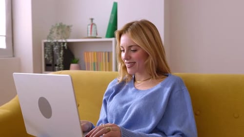 Woman Using Laptop on Couch at Home