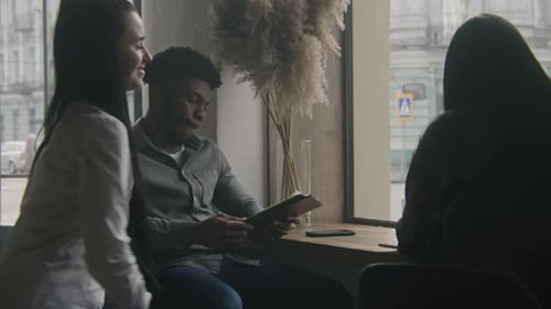 African American Man Looks Food Menu in Restaurant