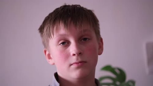 Boy Blinking Solemnly at the Camera Indoors