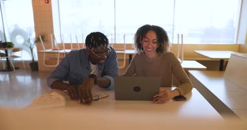 Happy multiracial business owners plan small business growth using laptop in restaurant