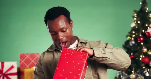 Christmas, gift and surprise with face of black man in studio for celebration