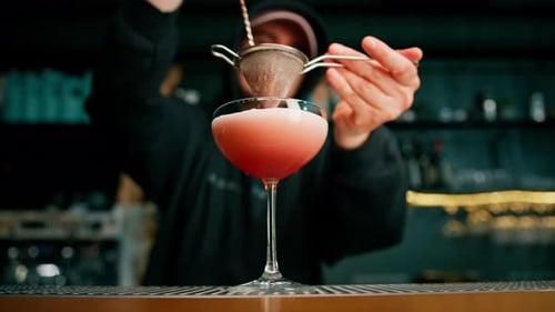 Bartender straining cocktail in bar environment