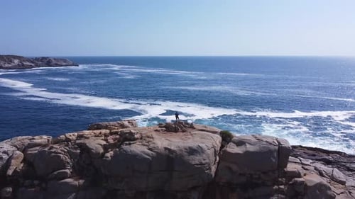 Man climbing rock in the sea. Look at the ocean from a rock. 4k