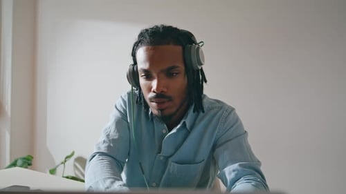 Young Man Working On Laptop Wearing Headphones Indoors