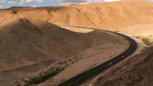 Aerial view of a Car heading north on a Desert highway with cloudy blue sky