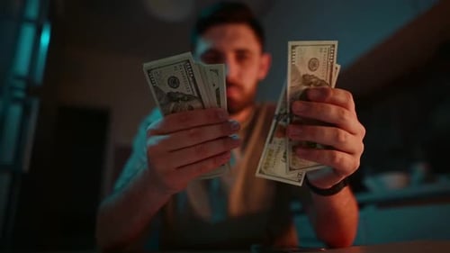 A man counts money in the kitchen at night