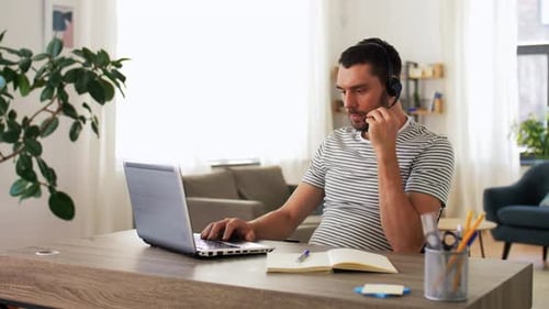 Man Working from Home Using Laptop and Headset