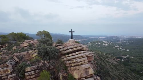 Black Cross Standing on a Rocky Cliff Overlooking a Vast Valley