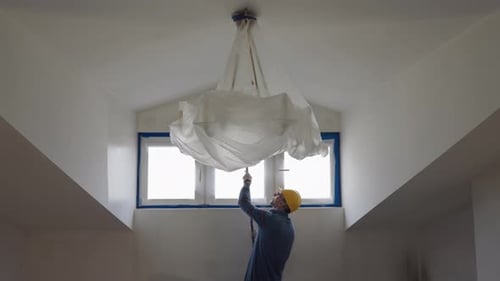 Ein Mann malt eine Wand mit einer Rolle und repariert das Zimmer im Dachgeschoss