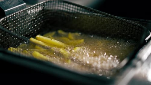 Closeup of French Fries Being Fried in Professional Kitchen in a Deep Fryer