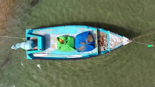 Kleines Fischerboot vor Anker in einer flachen Lagune, mit gepacktem Fischnetz an Bord