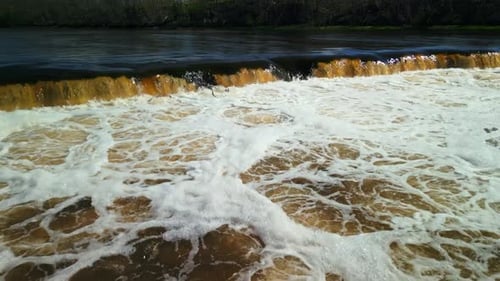 The River Flows Over Rocks Creating White Foam in Serene Nature with Natural Backdrop of Landscape