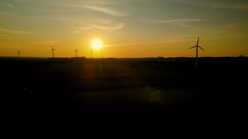 Wind turbines producing green energy. Windmill silhouette on the horizon. Aerial