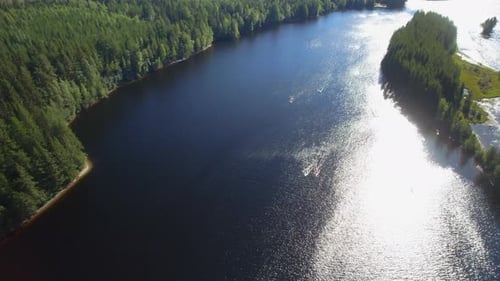 drone shot of a group of people out kayaking on a river in the forest