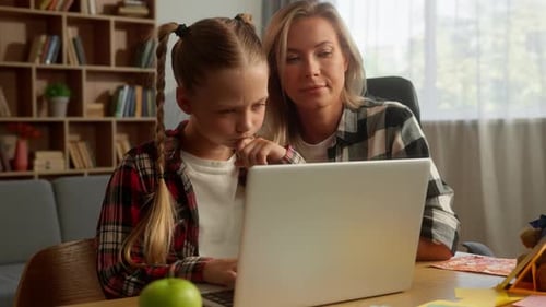 Woman and Child Use Laptop Together at Home