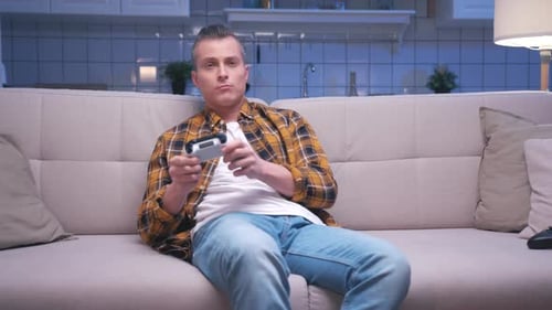 Man Plays Video Games on Couch at Home